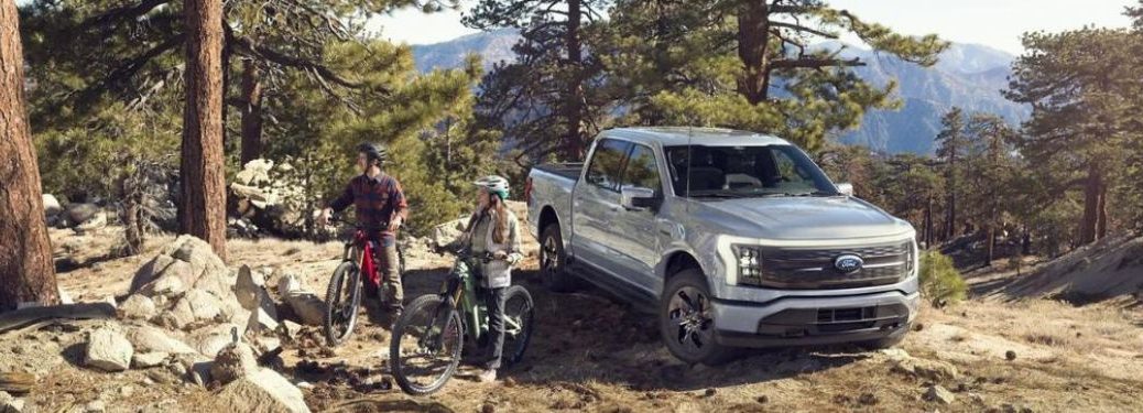 Two bicyclists next to a Ford F-150 Lightning.