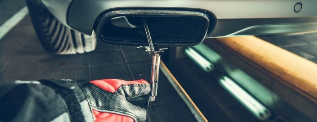 a technician fixing the muffler of a car