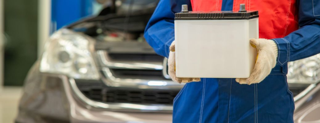 a technician holding a car's battery