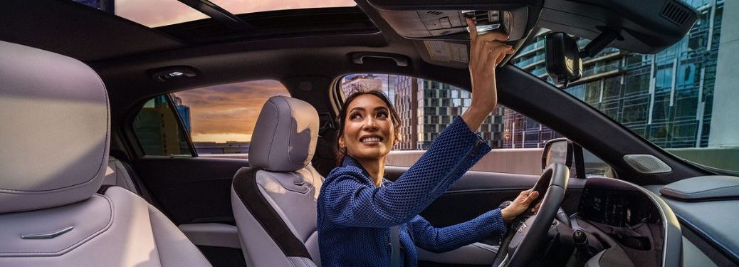a woman in driving seat opening sunroof of a 2025 Cadillac XT4