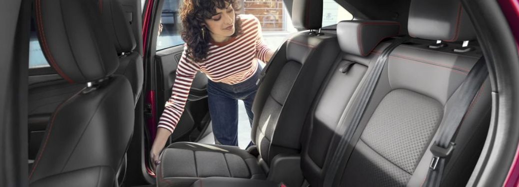 a woman sliding the second row seat of a 2025 Ford Escape
