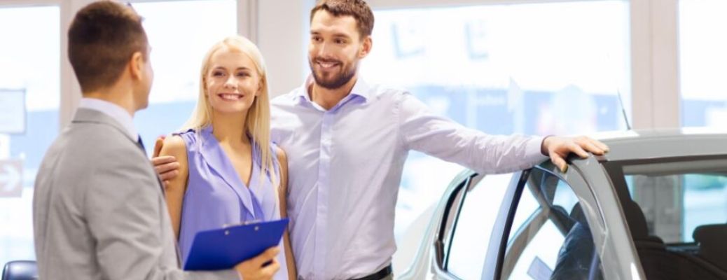a salesman talking to a couple buying a car