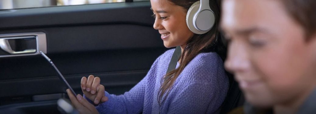 a girl wearing headphones looking at a tablet in a Ford with Connectivity Package