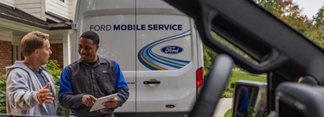 a man and technician talking with a Ford Mobile Service van in the background
