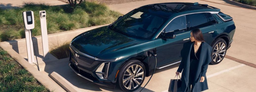 a woman walking away from a 2025 Cadillac LYRIQ at a charging station