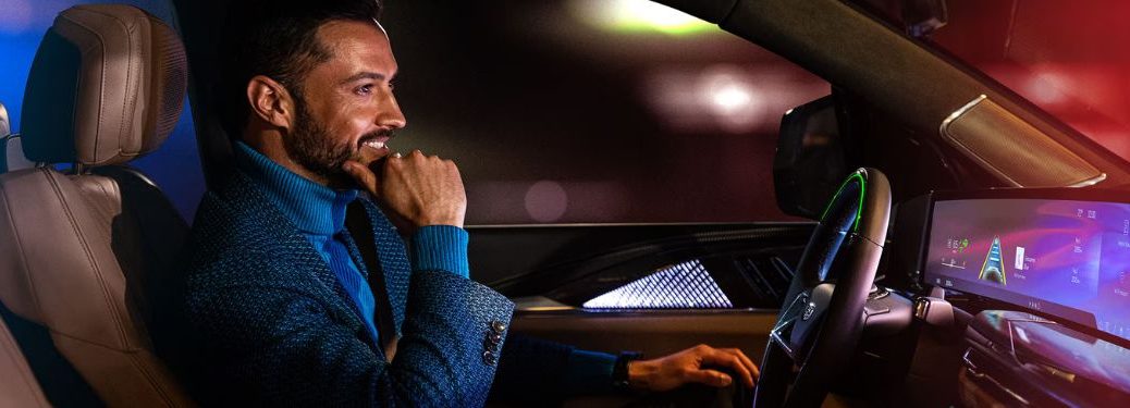 A man driving a Cadillac vehicle