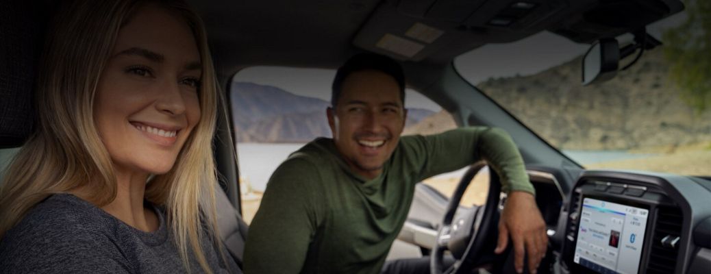 A couple smiling at from inside a Ford vehicle