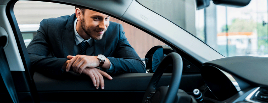 A man looking in the window of a car