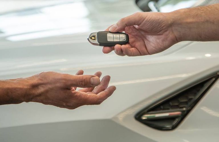 a hand giving Lamborghini keys in another