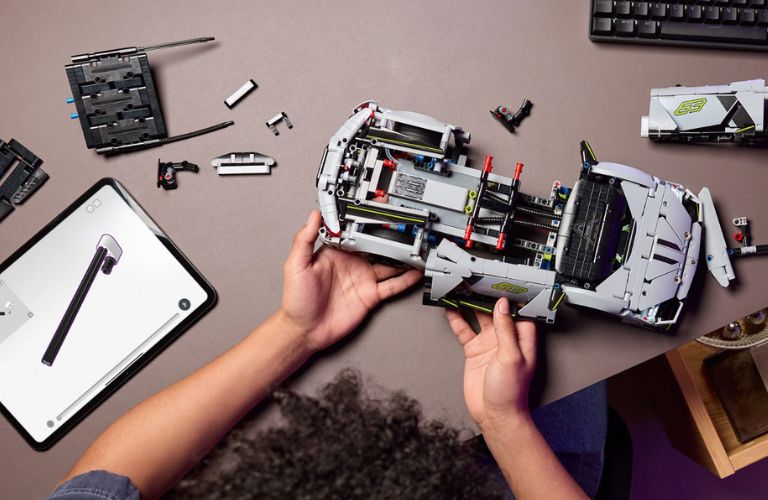 a kid's hand using Legos to create a Lamborghini