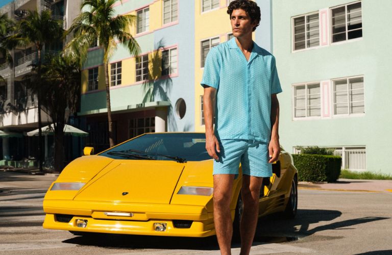 a man in blue clothing posing next to a Lamborghini
