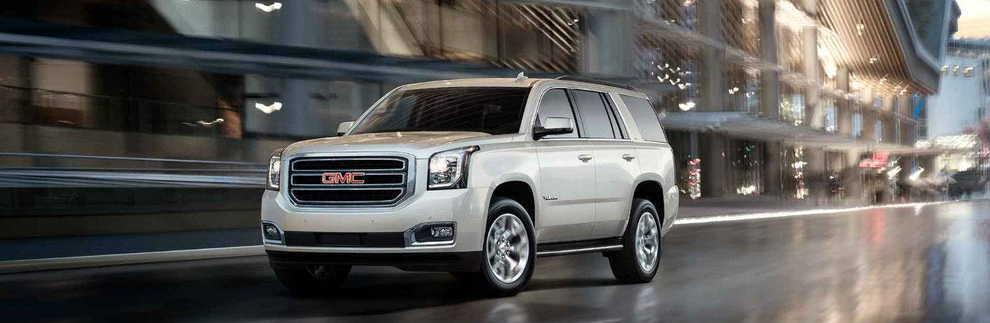 White GMC Yukon driving on city street at night