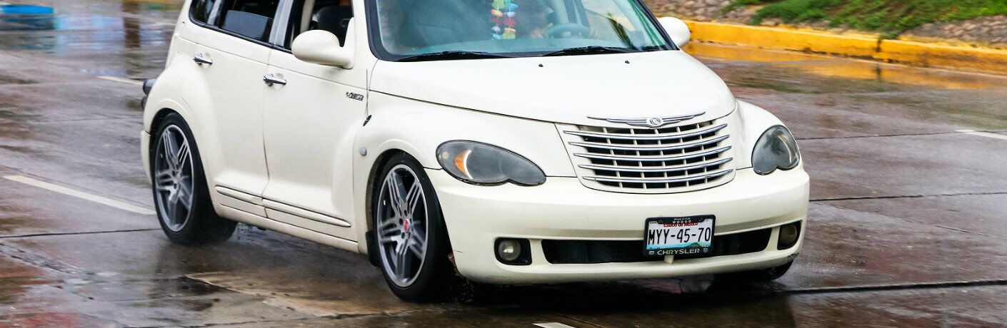 White Chrysler PT Cruiser driving on rainy city road