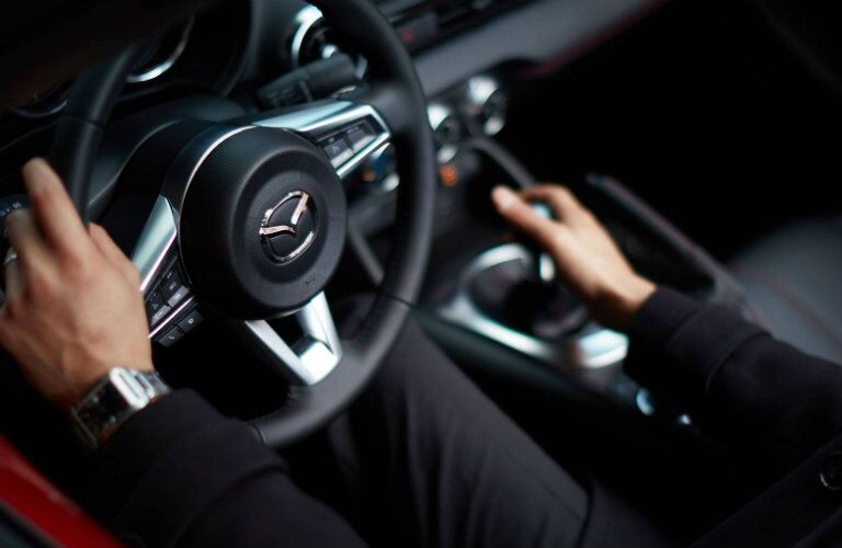 Man Holding the Steering Wheel of a 2018 Mazda MX-5 Miata RF