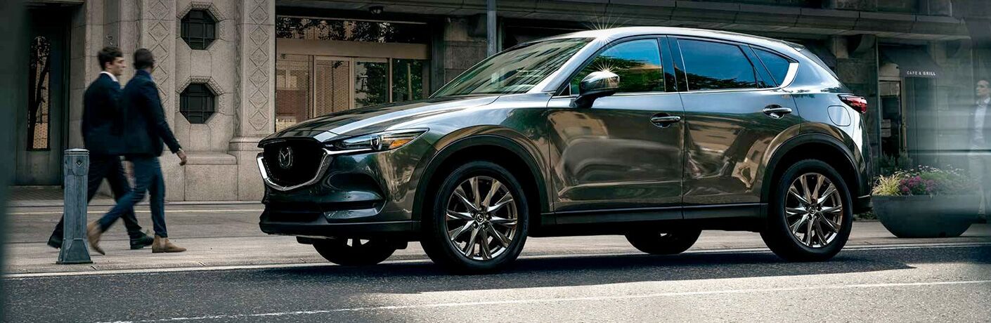 Two people walking by a grey 2019 Mazda CX-5