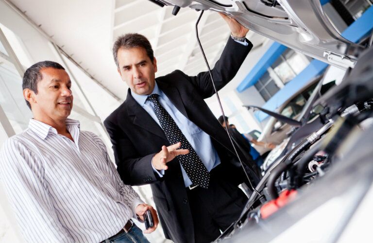dealership salesman showing a driver a new mazda
