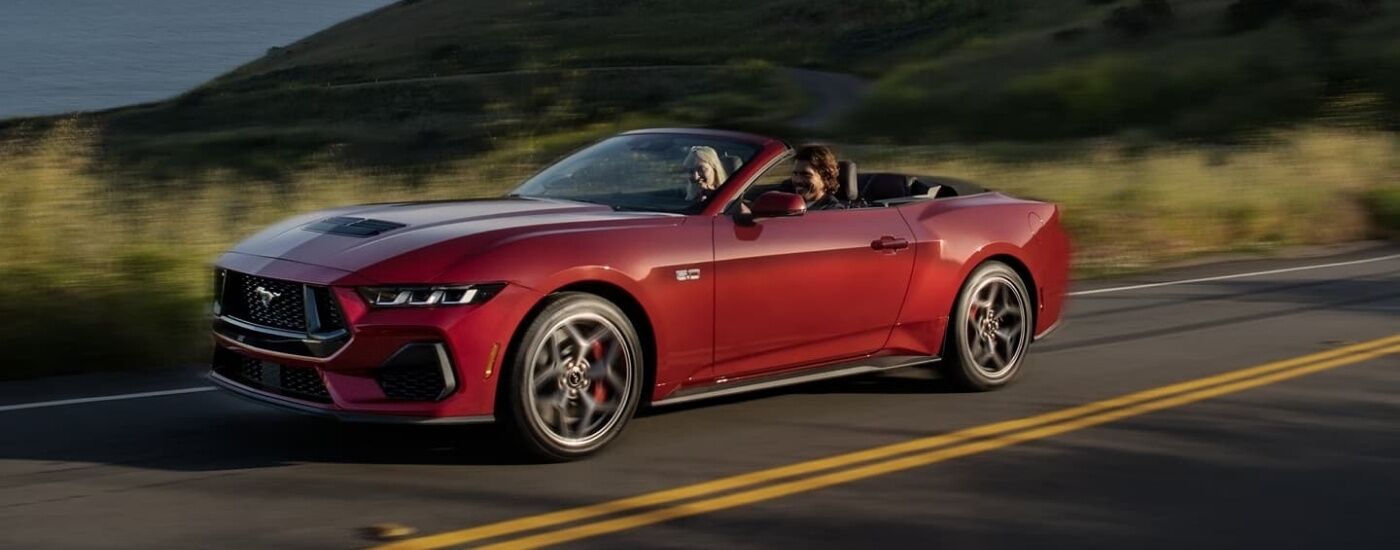 Maroon 2024 Ford Mustang GT driving on a highway