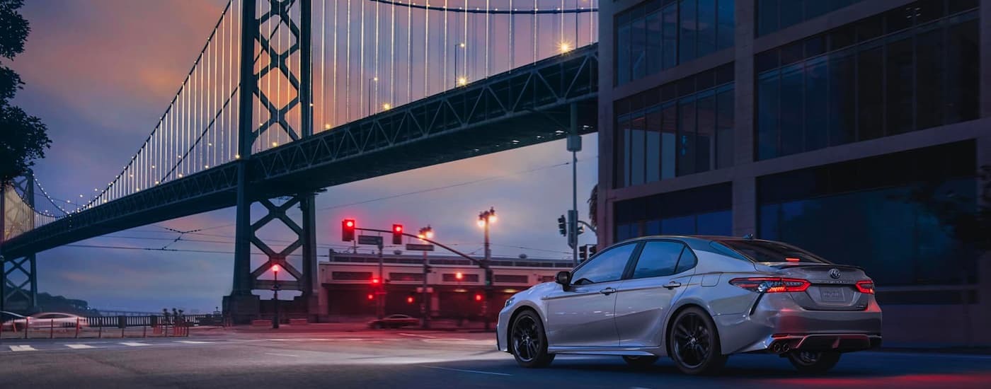 Grey 2020 Toyota Camry driving beneath a bridge.