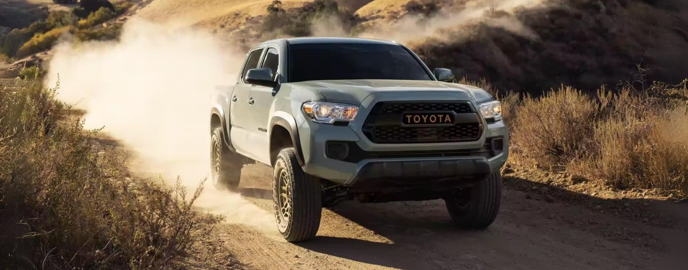 Grey 2023 Toyota Tacoma SR5 Trail Edition driving off-road on a trail.