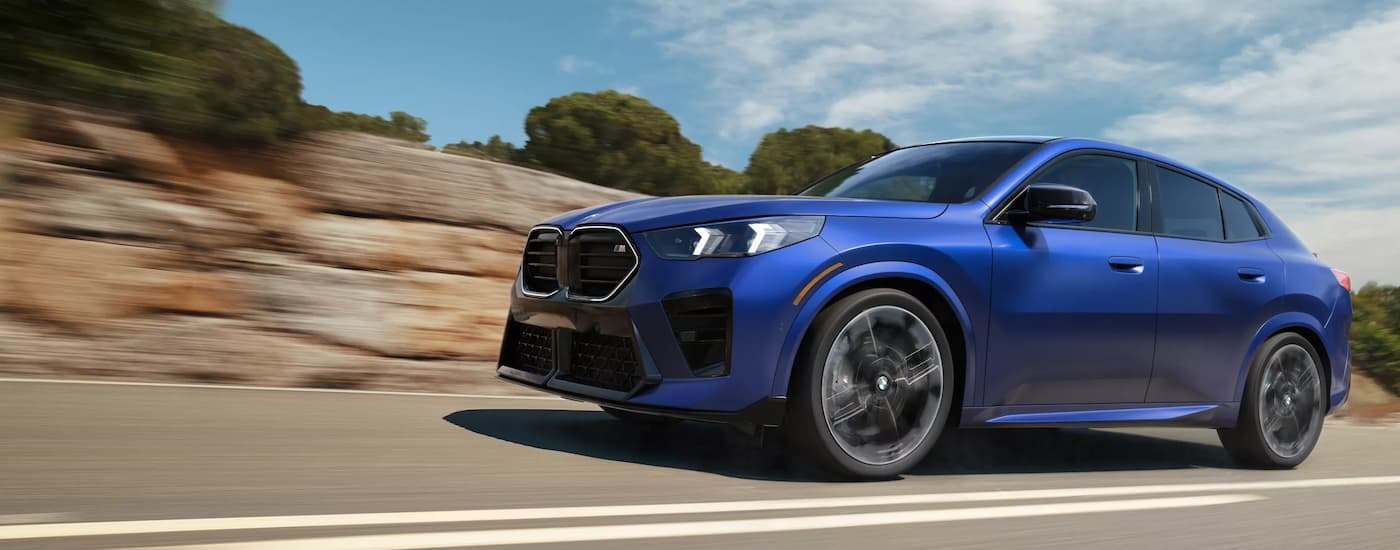Blue 2026 BMW X2 M35i driving down an open road.