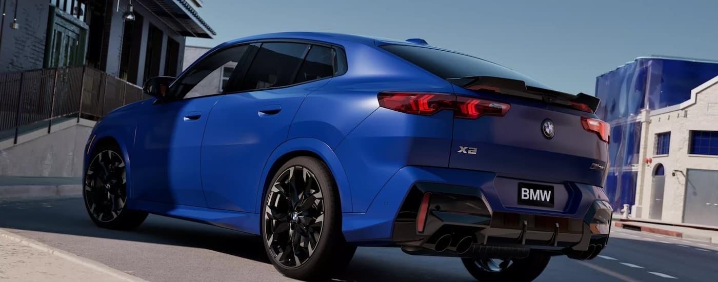Rear of a blue 2026 BMW X2 M35i parked in front of a building.