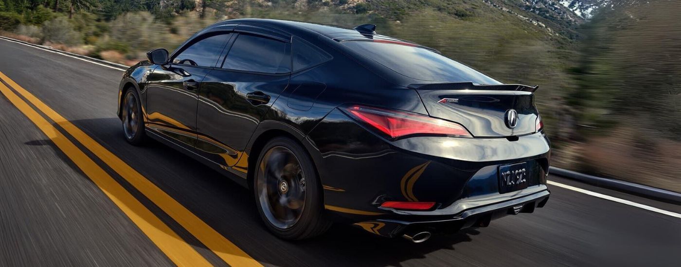 A black 2023 Acura Integra A-Spec driving on an open highway.