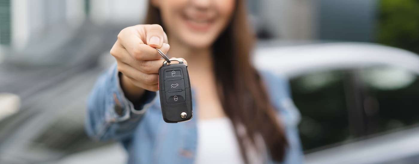 A woman is holding out a car key.