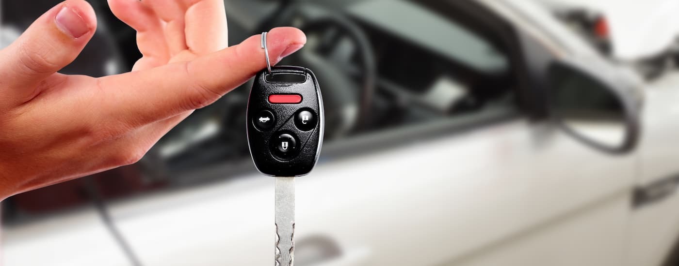 A hand is holding out a car key.