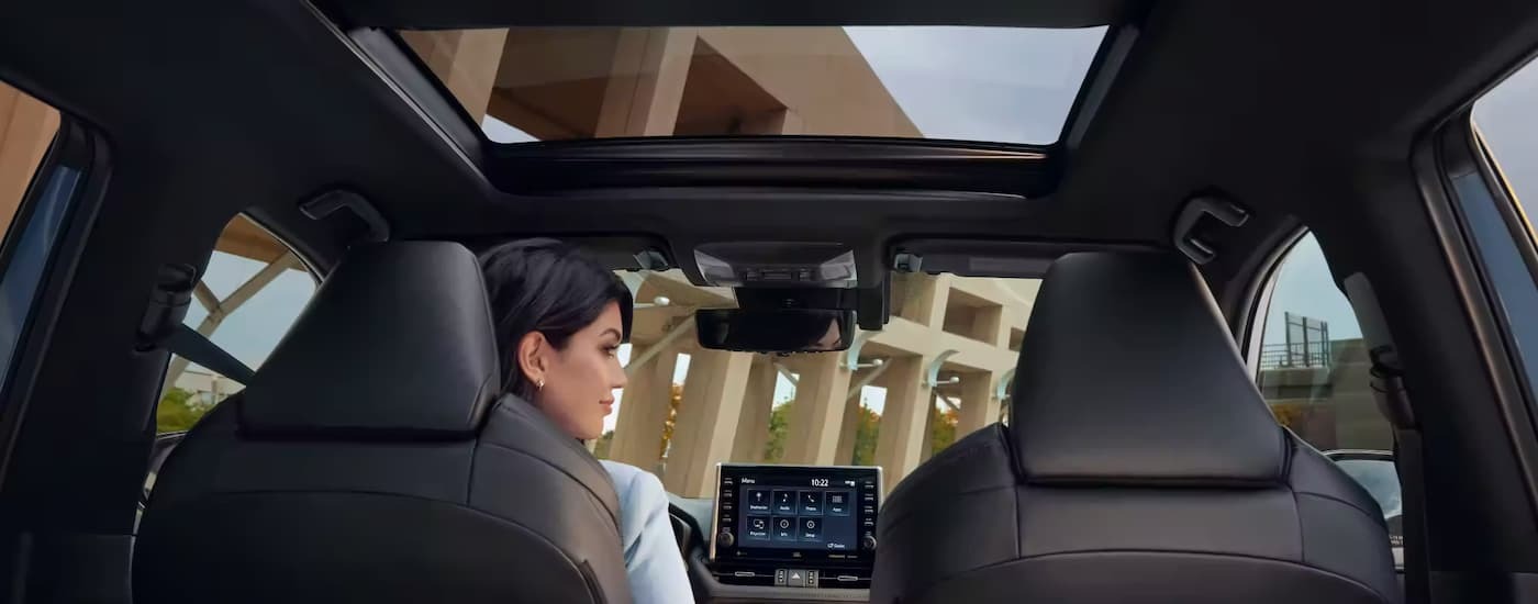 A woman is sitting in the drivers seat of a 2022 Toyota RAV4.