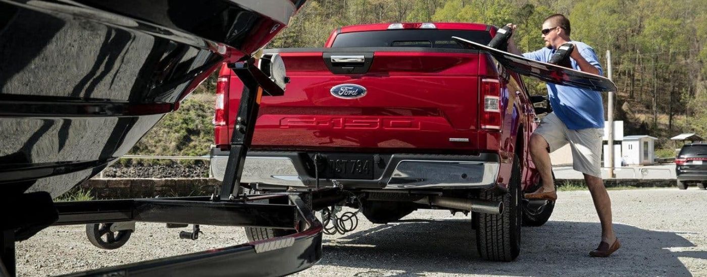 A person is shown loading a wake board into a red 2018 Ford F-150.