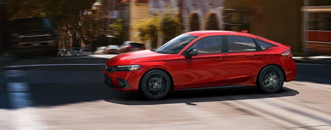 Red 2023 Honda Civic driving on a city street
