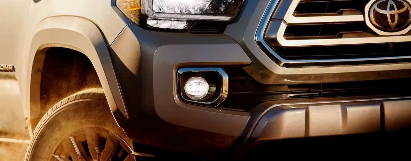 A close up of the grille and headlight on a grey 2023 Toyota Tacoma.