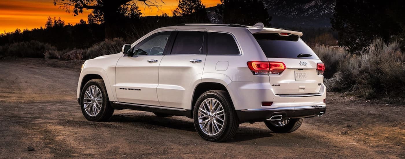 A white 2018 Jeep Grand Cherokee is parked on a dirt road after leaving a dealer with used cars for sale near Newark.
