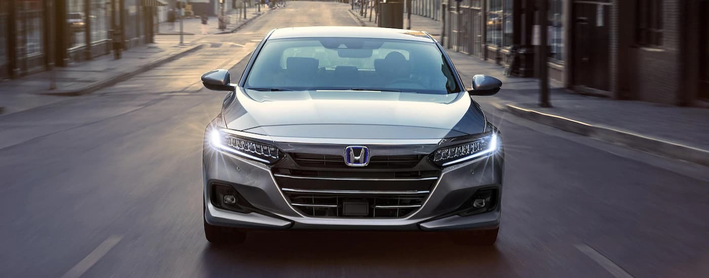 A front view of a silver 2022 Honda Accord Hybrid driving on a city street.