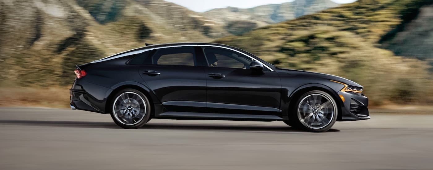 Side of a black 2021 Kia K5 driving on an open road