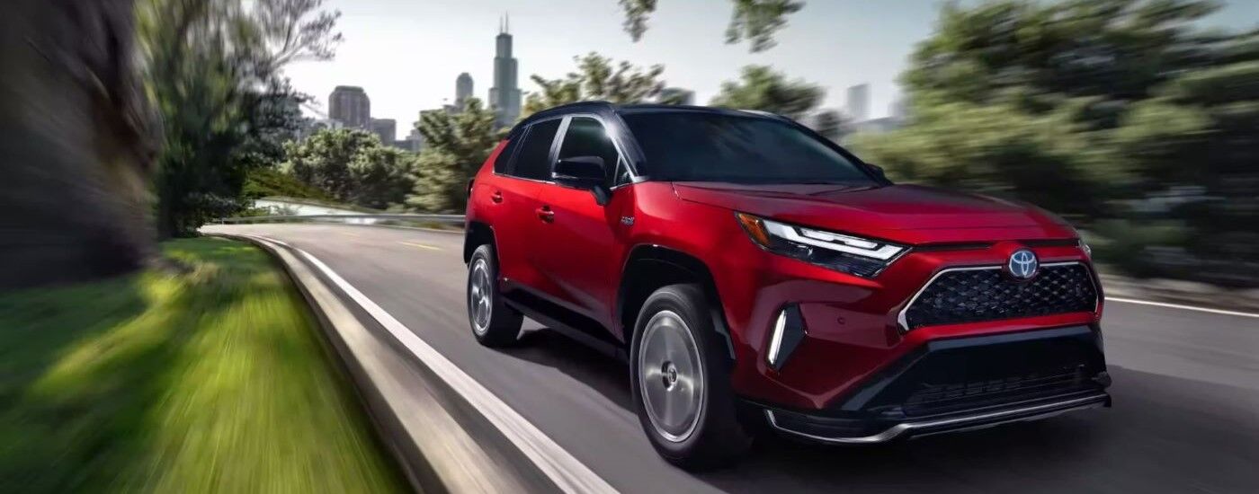 Red 2023 Toyota RAV4 leaving a dealership with used SUVs for sale near Hackensack.