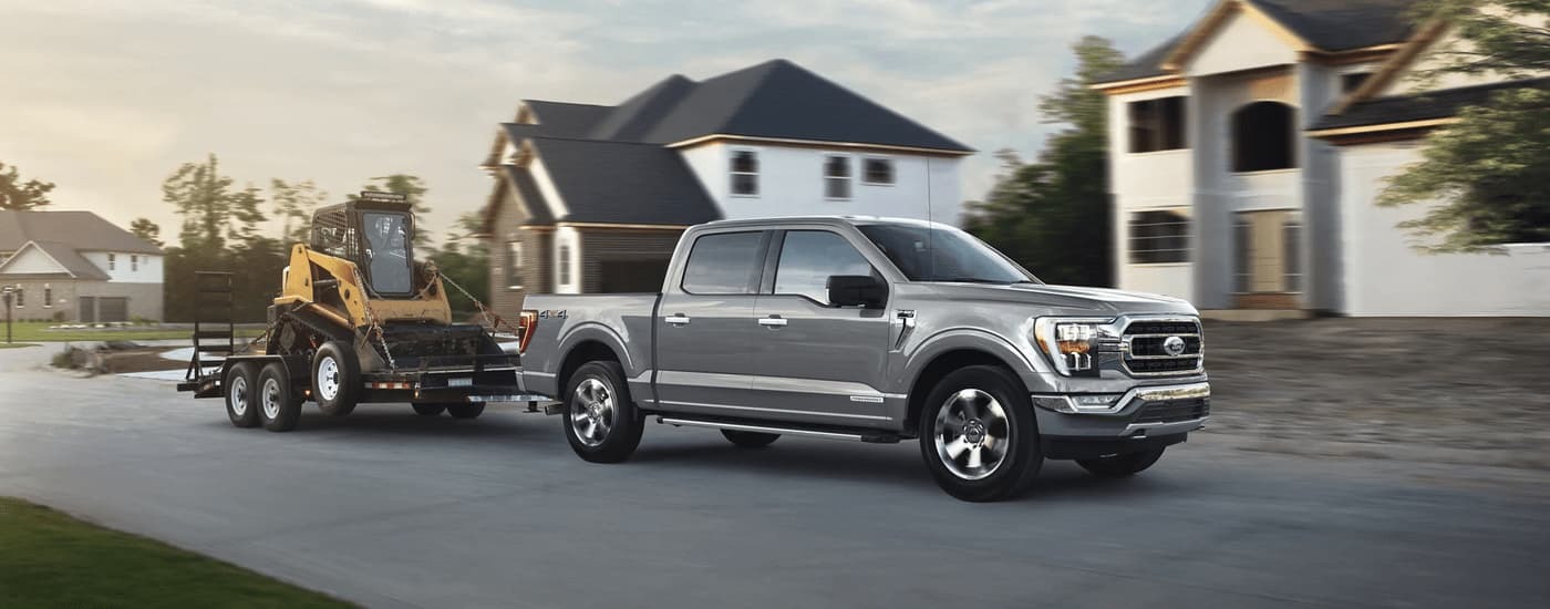 Grey 2018 Ford F-150 towing heavy machinery on a trailer