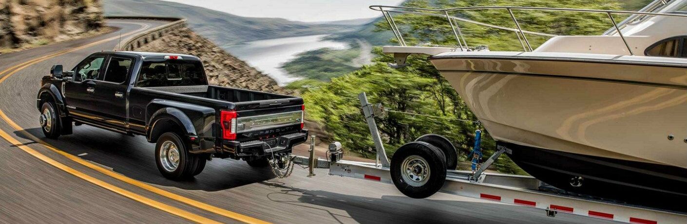 Black 2019 Ford Super Duty F-350 towing boat on winding mountainous road