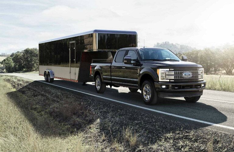 Black 2019 Ford Super Duty F-350 Platinum towing trailer down empty country road