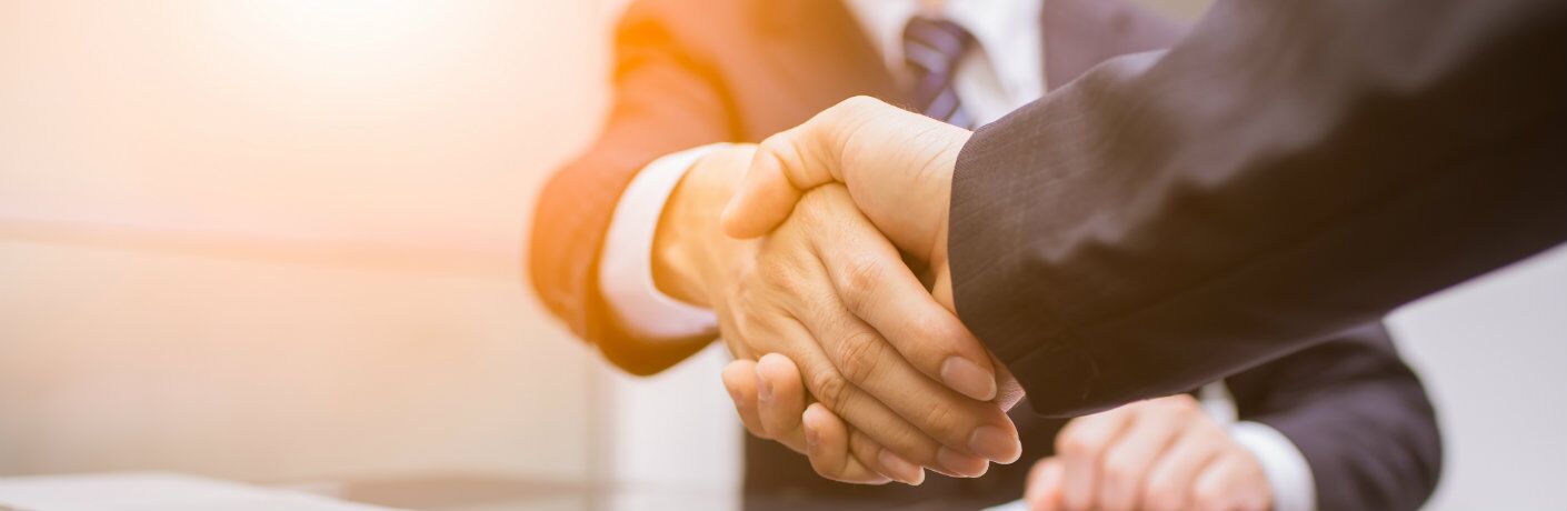 Arms of men in business suits shaking hands