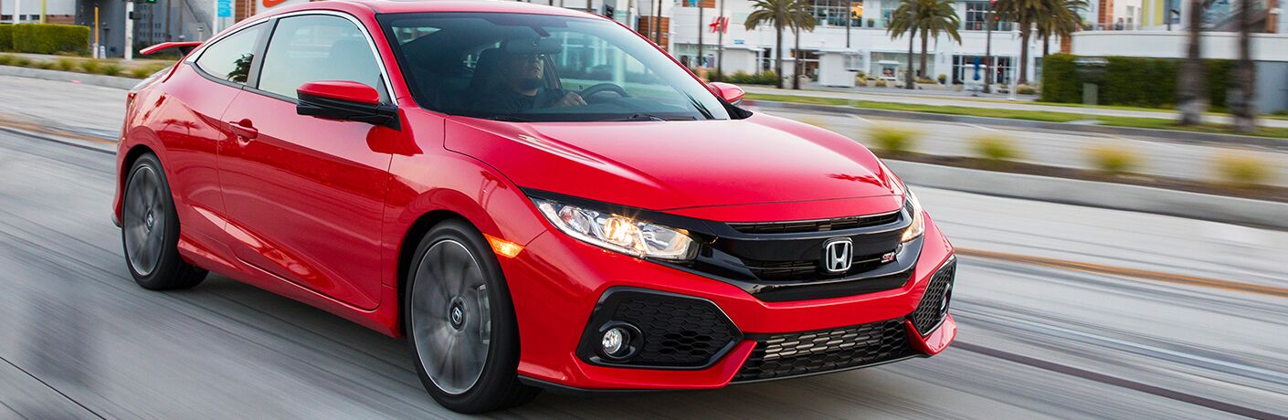 side view of a red 2018 Honda Civic Si driving past palm trees