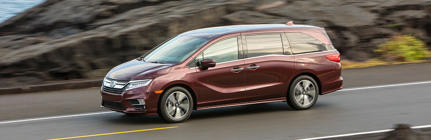 side view of the 2019 Honda Odyssey driving past rocks