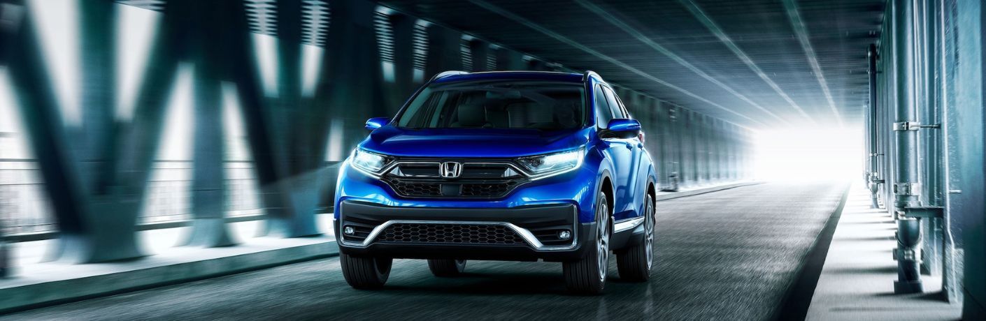 A blue 2022 Honda CR-V Hybrid Touring driving in the underpass.