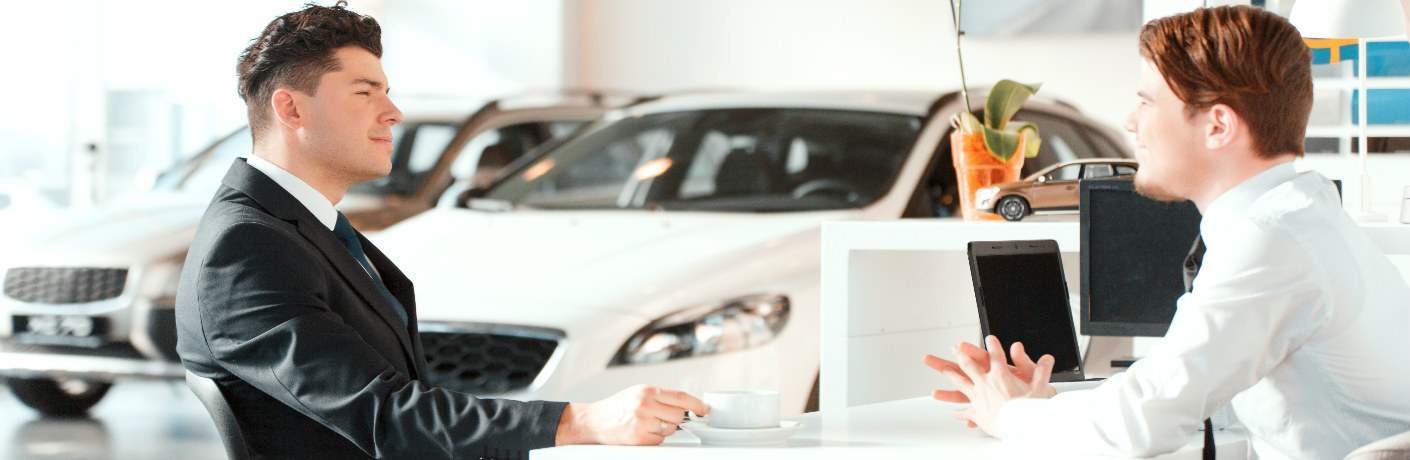 salesman and customer sitting across from each other in auto dealership