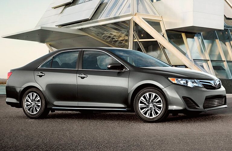 A grey Toyota sedan is parked beside a mysterious modern structure.