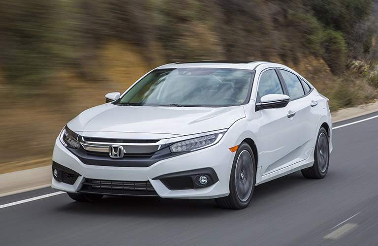 White 2017 Honda Civic Sedan drives down a highway.