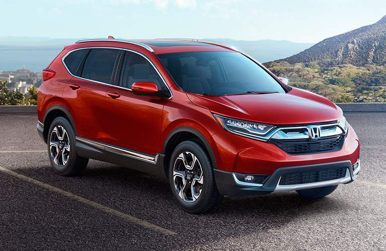 red 2018 Honda CR-V with a background of water and cliffs