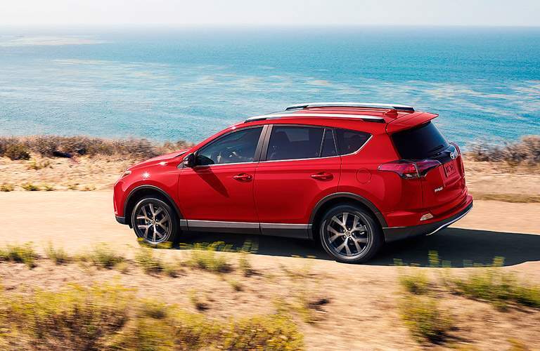 red 2017 Toyota RAV4 driving by water