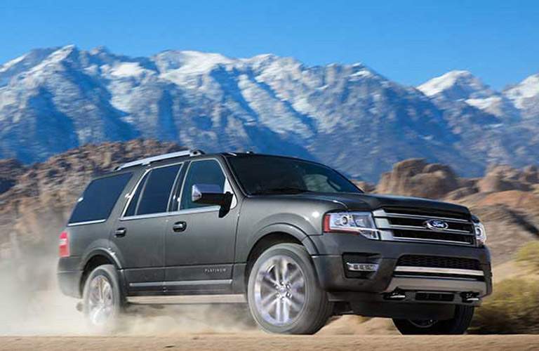 2017 Ford Expedition driving in dust with a background of mountains