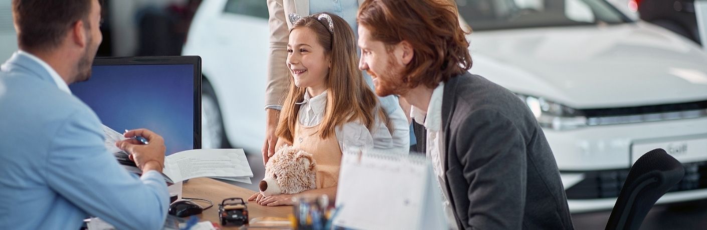 Image showing a young girl and a man talking to a car salesman at a dealership